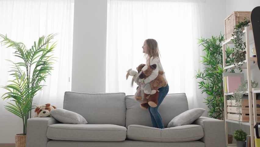 Kid throwing soft toys and jumping on sofa at home. Hyperactivity concept | Shutterstock HD Video #1101109869