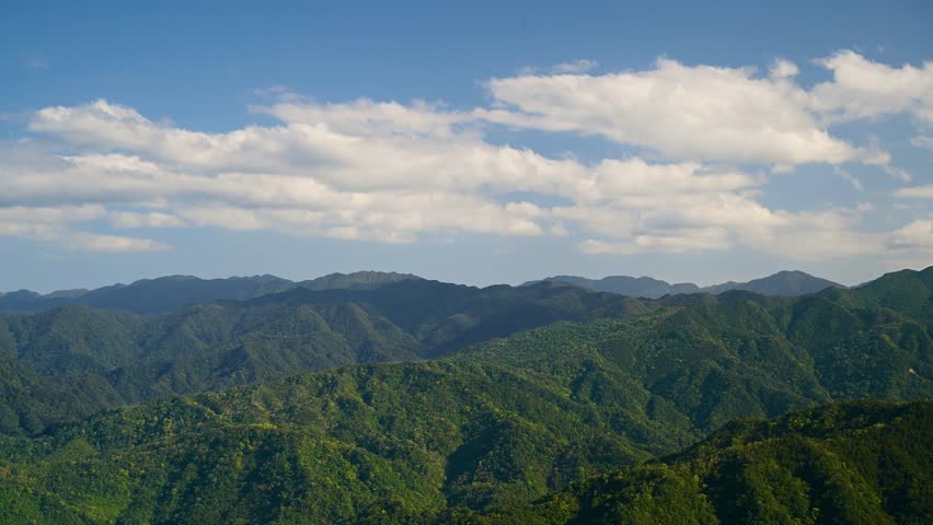 White clouds and blue sky above the green mountain. It