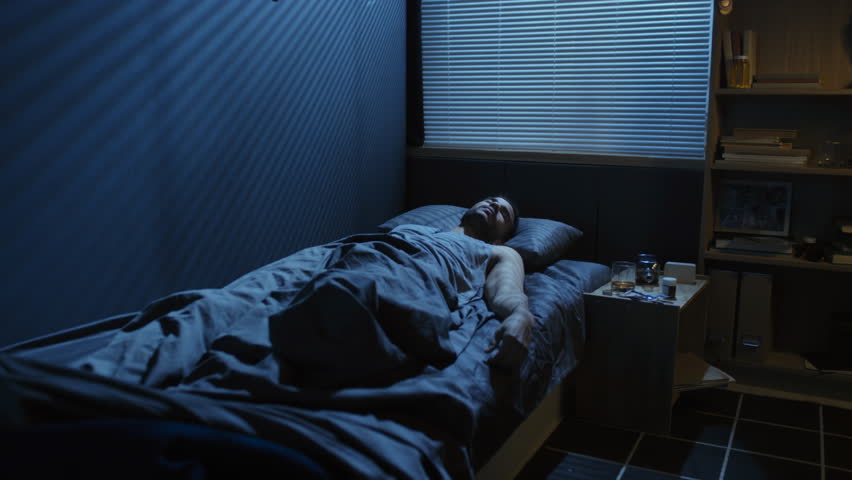 Handheld shot of young man sleeping in bedroom at home experiencing scary nightmare waking up late at night Royalty-Free Stock Footage #1101110117