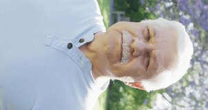 Vertical video portrait of happy senior caucasian man smiling in garden, in slow motion. Healthy, active senior lifestyle.