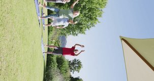 Vertical video of happy diverse senior men and women doing yoga in sunny garden, in slow motion. Healthy, active senior lifestyle.