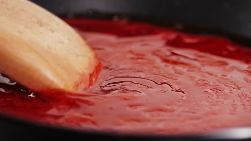 Classic homemade Italian tomato sauce with basil for pasta and pizza in the pan. Chef cooking traditional Italian food.