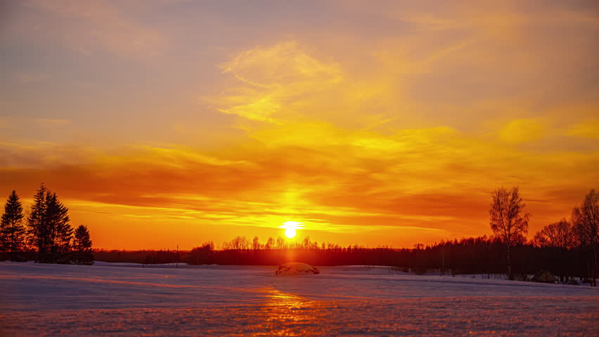 Golden sunset over a snowy countryside landscape - time lapse