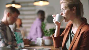 Coffee, laptop and profile of business woman in office drinking espresso, caffeine or cappuccino while working on a project with coworkers. Tea, computer and female employee in workplace with staff. - Powered by Shutterstock - Get 15% off with code: PIKWIZARD15