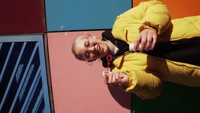 vertical video slow motion curvy LGBT woman short hair girl blowing soap bubbles laughing and being happy yellow colors background