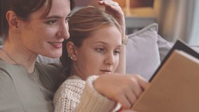 Medium closeup of young Caucasian military woman together with her pre teen daughter looking at photos in photo album remembering army time - Powered by Shutterstock - Get 15% off with code: PIKWIZARD15