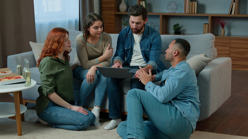 Four ethnic friends gathered at home use laptop application talking choose movie on computer share ideas multiracial diverse men women discuss friendly conversation make internet order food delivery Royalty-Free Stock Footage #1101131057