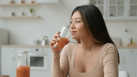 Korean woman drinking fresh smoothie orange juice. Asian vegetarian girl tasting glass of vitamin fruity cocktail peach drink healthy diet weight loss healthcare nourishment morning detox in kitchen Arkistovideo