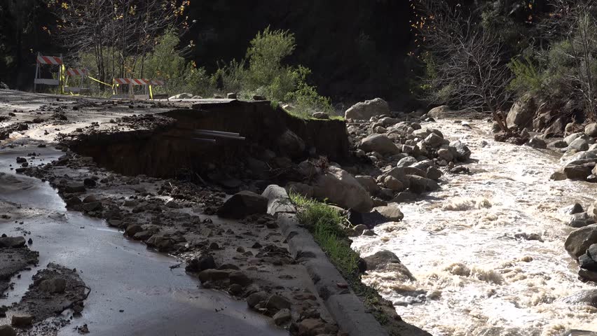 Santa barbara, california - circa 2023 - a river flows past a road demolished by a storm and flood in santa barbara, california.
