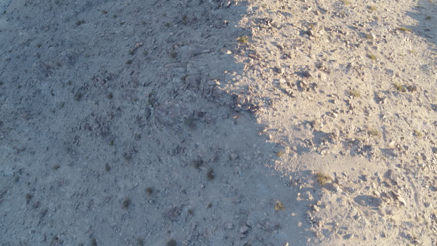 Top down aerial above half shaded rocky desert hill in Johnson Valley in southern California