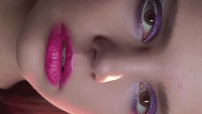 Vertical video. 90s makeup. Retro look. 2000s fashion. Closeup portrait of teen girl face with purple color eyeshadow pink lips artistic visage.