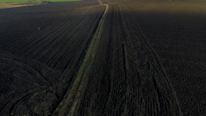 Landscape of plowed up land on agricultural field on sunny autumn day. Flying over plowed earth with black soil. Ground earth dirt priming. Agrarian background. Black soil. Aerial drone view. Royalty-Free Stock Footage #1101138007