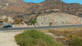 MARQUIS LOS CABOS MEXICO-2021: Lonely Road Beside A Rocky Hill With Several Cars Traveling In The Opposite Direction