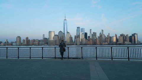 Guy standing at the waterfront in Jersey City and watching the skyline of Manhattan - drone photography – Video có sẵn