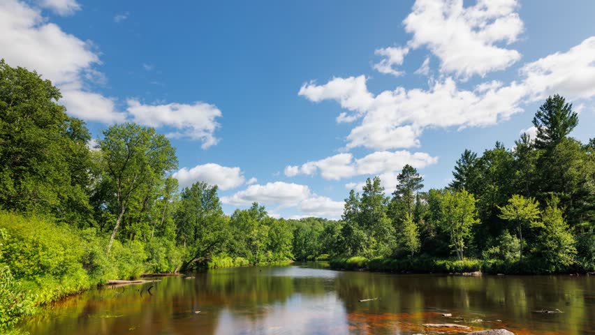 Time lapse of the clouds moving above Kettle River surrounded by forest in Minnesota.