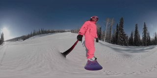 Snowboarding or skiing on winter snowy slope. Ski resort, winter sport. POV riding a snowboard. Rider in pink jacket, helmet. 360 degrees vr virtual reality video