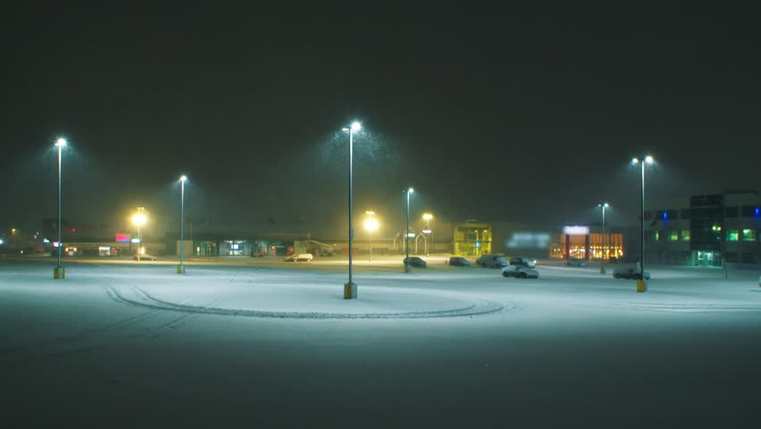 Large parking lot at night in a heavy snow storm. Snowstorm in winter in Halifax, Canada. View of an empty car park with tall night lights and heavy storm snow.