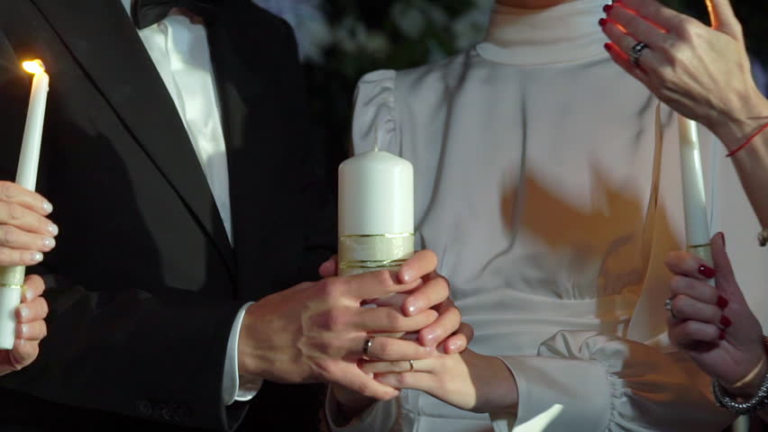 Two people light one candle against the other. White traditional candles for a holiday, church, party. Family hearth at a wedding. | Shutterstock HD Video #1101145543