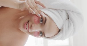 Vertical video of happy caucasian plus size woman applying under-eye patches in slow motion. Spending quality time at home, body inclusivity concept.