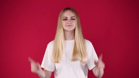 4k slow motion video of one girl pointing at camera and showing thumb ups over pink background.