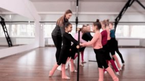 Sportive little girls, children, gymnasts training with coach indoors. Stretching exercises with barre equipment. Concept of sportive lifestyle, childhood, education, health, professional sport.