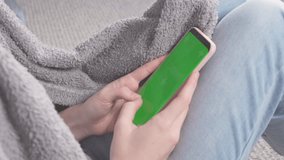 Teenager girl typing on phone with green screen. Phone with greenscreen and chroma key for copy space. Chromakey mock up with tracking markers. Tap to click on centre of screen