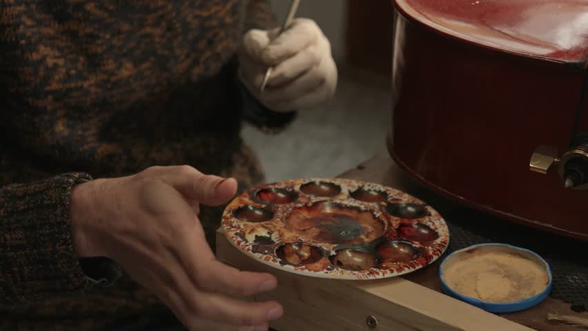 Closeup of luthier repairs cello by painting a scratch with a brush in a workshop | Shutterstock HD Video #1101154431