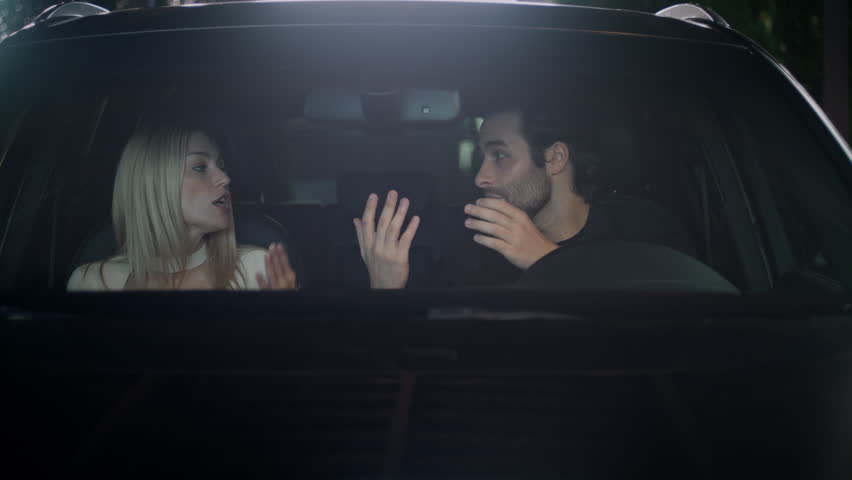 View through the front window of a car. The couple swears in the car. The boy and girl are arguing and screaming at each other. The tension between the partners was high. The girl is waving her hands. Royalty-Free Stock Footage #1101156287
