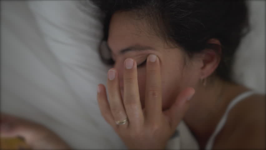 Woman rubbing eye laid in bed looking at phone. Tired sleepy female person rubs eye with finger Royalty-Free Stock Footage #1101156447
