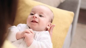 Close up portrait of adorable little baby infant laying on mother legs and enjoying time together at home Mom holding her baby's hand gently and soothes the child with his pleasant voice indoors - Powered by Shutterstock - Get 15% off with code: PIKWIZARD15