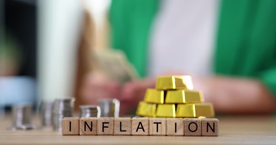 Word inflation and gold bars and stacks of coins on office table