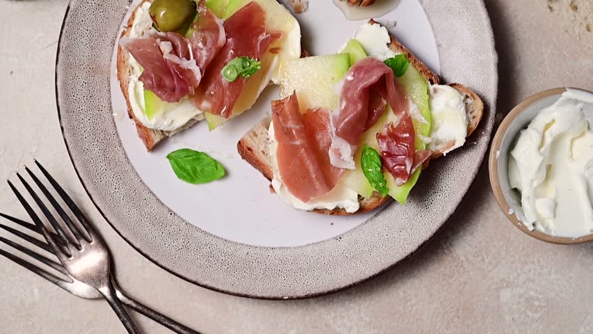 Melon with prosciutto toast with basil and honey. Antipasti snack.