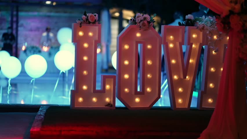 Illuminated Love sign in large letters at a wedding reception by decorated swimming pool Royalty-Free Stock Footage #1101164059