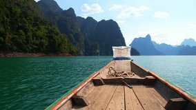 Immerse yourself in nature's wonder on a long-tailed boat tour of serene lake, surrounded by limestone mountains and emerald water. (Cheow Lan Lake, Khao Sok National Park, Thailand). 4K HDR

