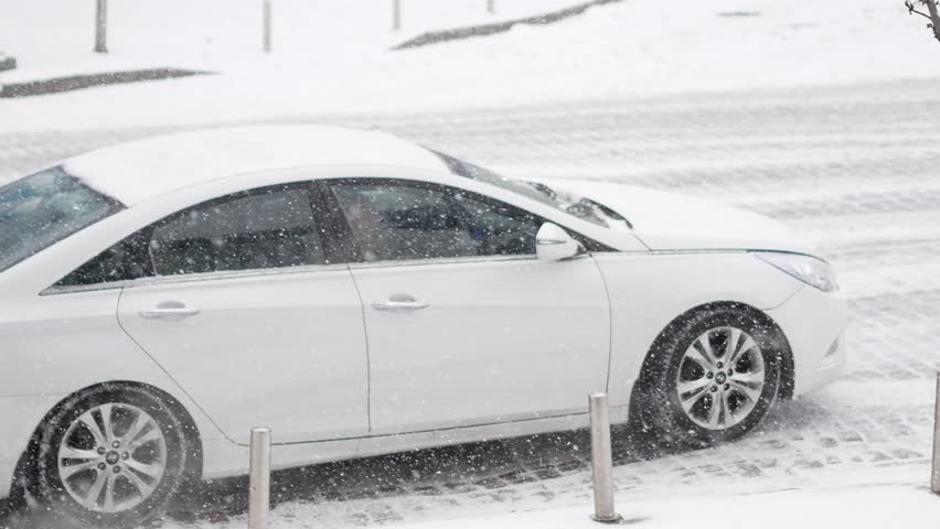 A car with summer tires skids on a snowy road cobblestone during heavy snowfall. A car slides on icy road on cold winter day | Shutterstock HD Video #1101166383