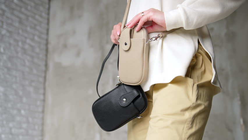 Little handbags demonstration. Unrecognized woman holding similar purses of two different colors. Close up.