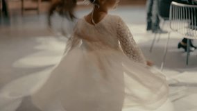 A little girl in a white dress is spinning. Video shooting in slow motion