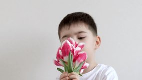 cute kid holding bouquet of tulips ,box gift sitting on bed giving,gift for mother march 8th women international day.child smelling tulip holding on nose.tulips in pants with phone calling spring - Powered by Shutterstock - Get 15% off with code: PIKWIZARD15