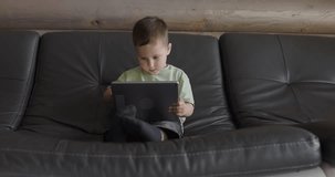 Young boy playing in a child development app on a digital tablet in a living room
