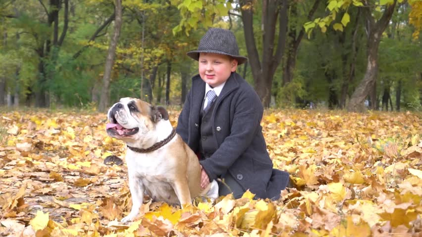 Friends, baby and dog are sitting together in beautiful golden leaves. Autumn 