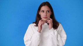 4k video of one girl planning something by putting his hands to his head over blue background.