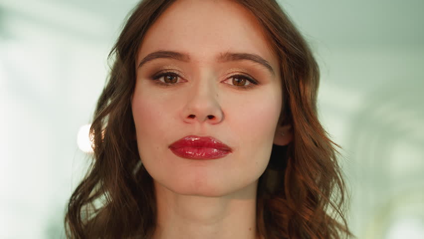 Young woman with professional makeup looks in camera smiling. Portrait of positive female person with ginger hair on blurred background closeup | Shutterstock HD Video #1101183409