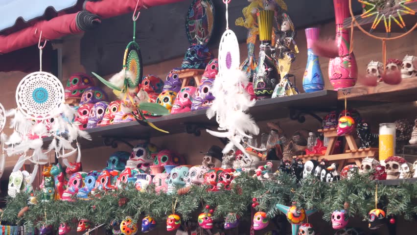 Mexican souvenirs on market stall, colorful painted skulls and dream catchers. Multicolor vivid ethnic ornaments, bazaar or marketplace. Ceramic crafted death symbol for sale on counter. Day of Dead. Royalty-Free Stock Footage #1101185201