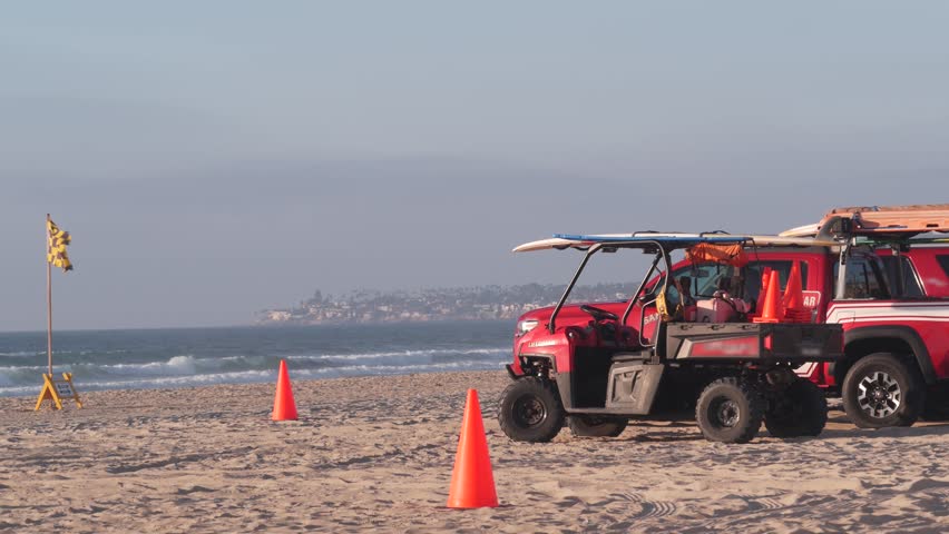 Lifeguard red pickup truck, life guard auto on sand, California ocean beach USA. Rescue pick up car on coast for surfing safety, lifesavers 911 vehicle, sky and sea waves. Seamless looped cinemagraph.
