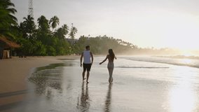 Silhouettes of a young happy couple holding hands and walking on the beach together enjoying summer back view. Boyfriend and girlfriend relax and walk at the seaside hugging and kissing at sunrise. - Powered by Shutterstock - Get 15% off with code: PIKWIZARD15