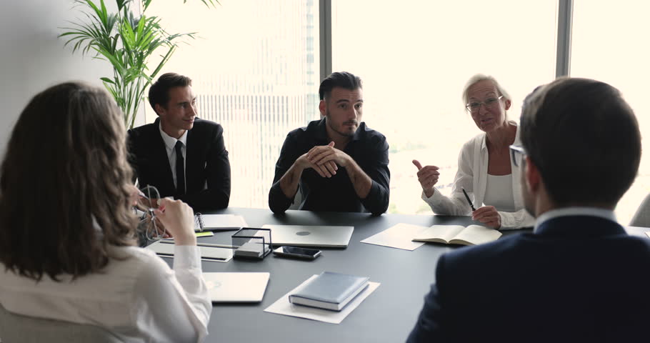 Serious businessman telling about joint project engaged in group meeting with workmates in board room. Executive manager convinces to clients buy company services during negotiations event in office Royalty-Free Stock Footage #1101193101