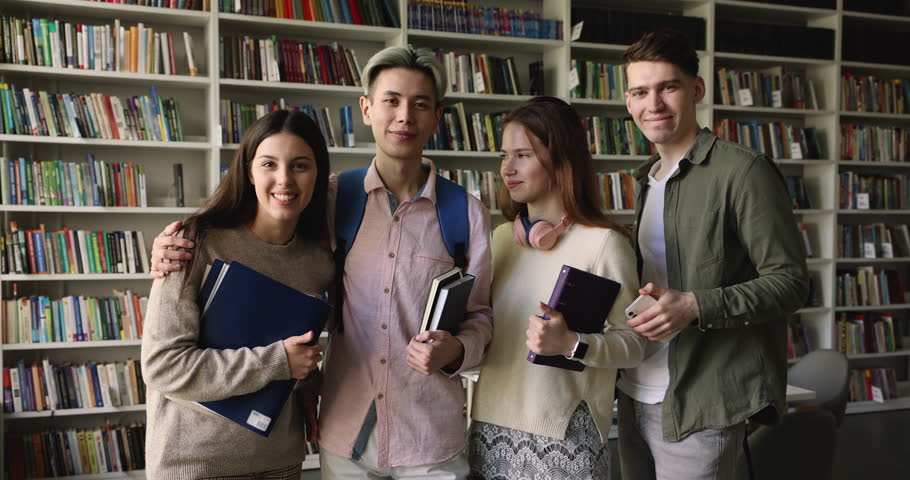 Multiethnic team of young college students posing in library, looking at camera, standing together, hugging, showing like thumb up gestures, peace, victory fingers, smiling, laughing, shouting Royalty-Free Stock Footage #1101193223
