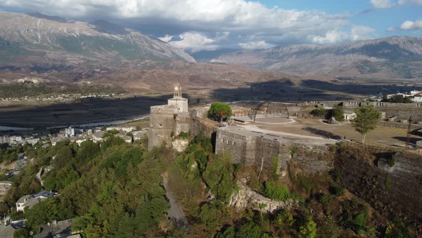 Medieval fortress with clock tower in Gjirokastër, Albania. UNESCO World Heritage Site. Historical buildings, architecture and cultural heritage. Castle of Gjirokaster, aerial drone view.