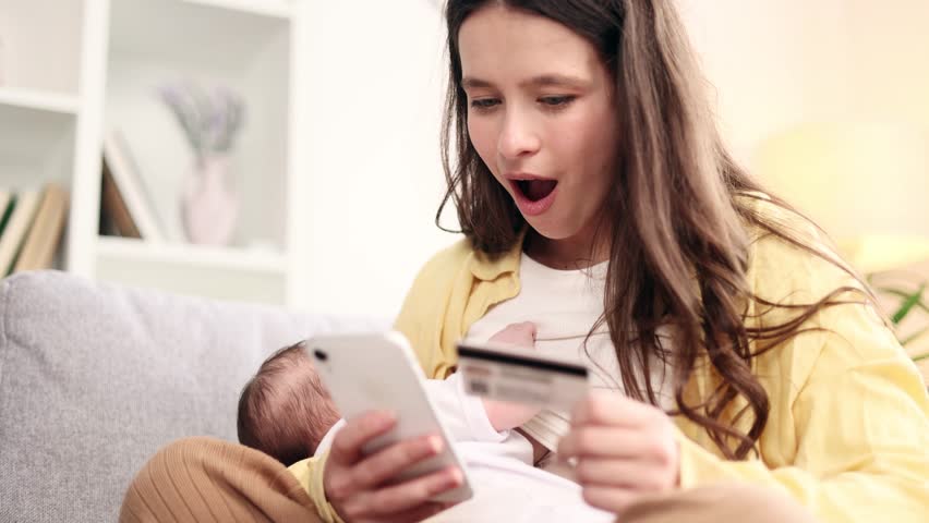 Pretty young woman mother breastfeeding her baby while scrolling on smartphone find wow incredible news promotion sale with credit card for making order buy product online shopping at light home | Shutterstock HD Video #1101194109