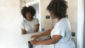 Young african woman brushing her teeth in the bathroom using ecological toothbrush. Cleaning teeth in the morning time.